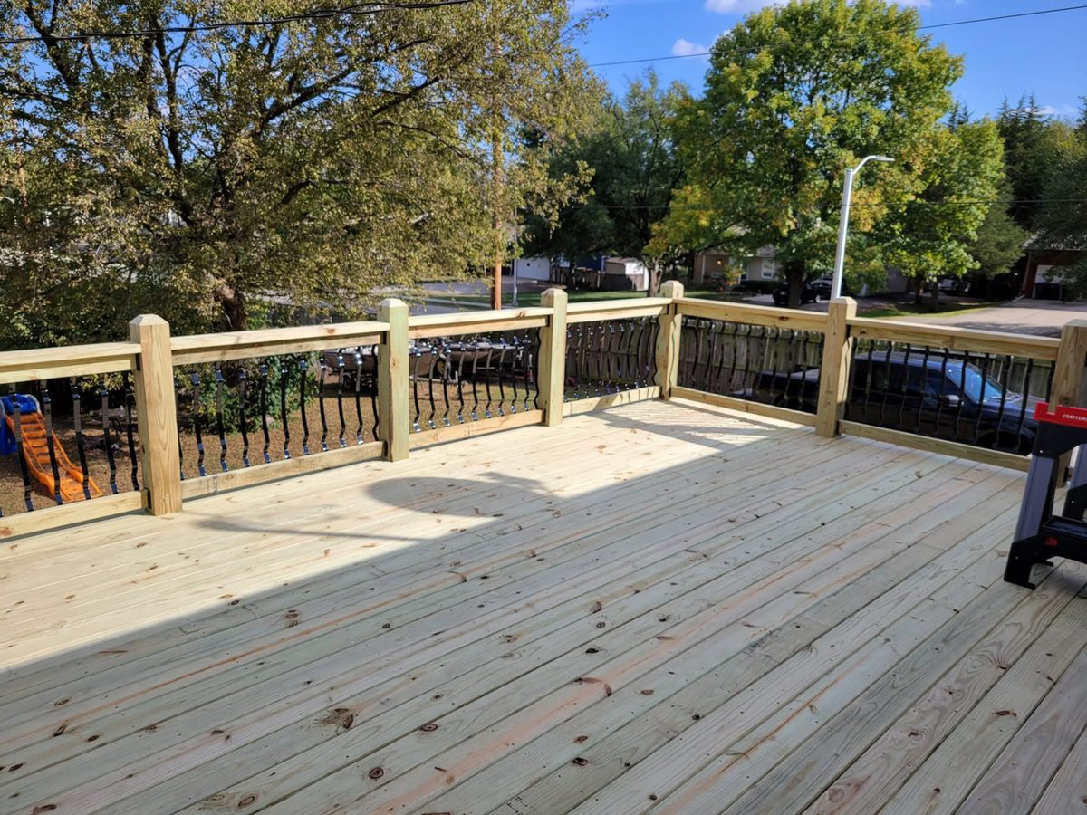Wood deck with black metal balusters and stairs down to the lower outdoor area