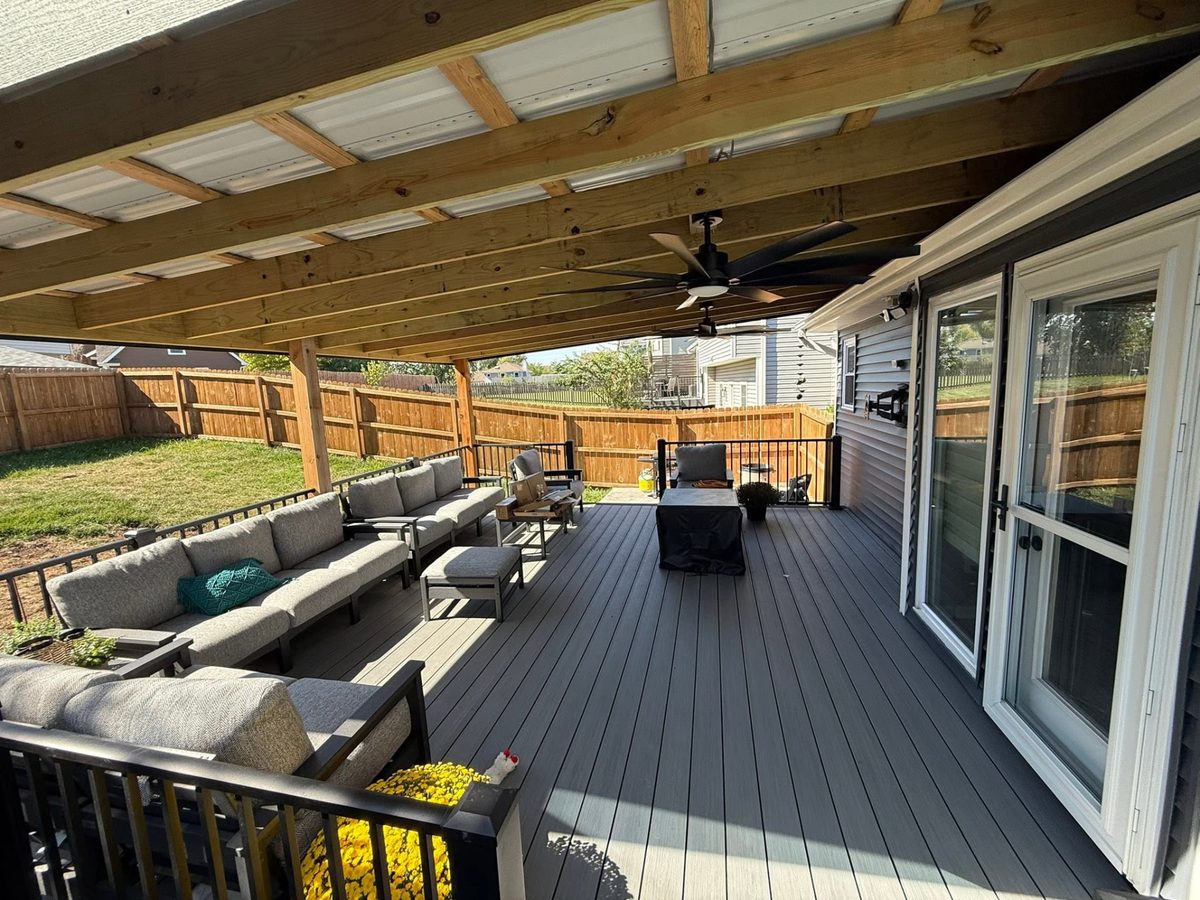 Covered two-tone deck with sectional seating and a ceiling fan